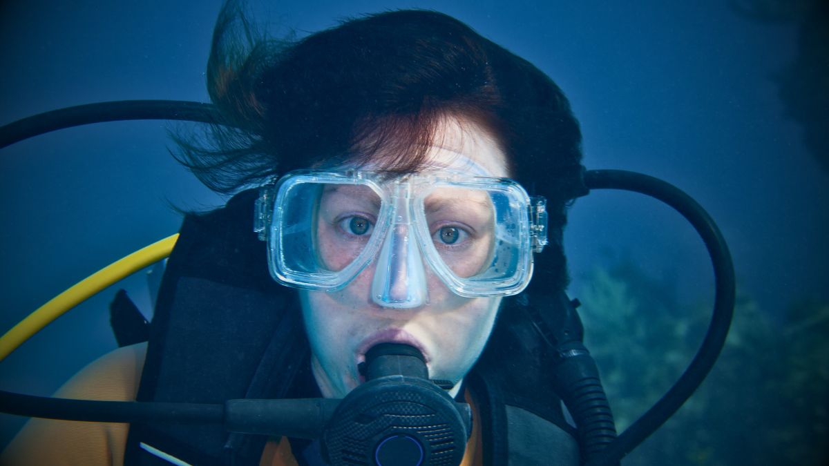 Excited PADI Open Water student with regulator breathing on first certification dive showing wonder and joy with instructor nearby in Costa Rica tropical waters