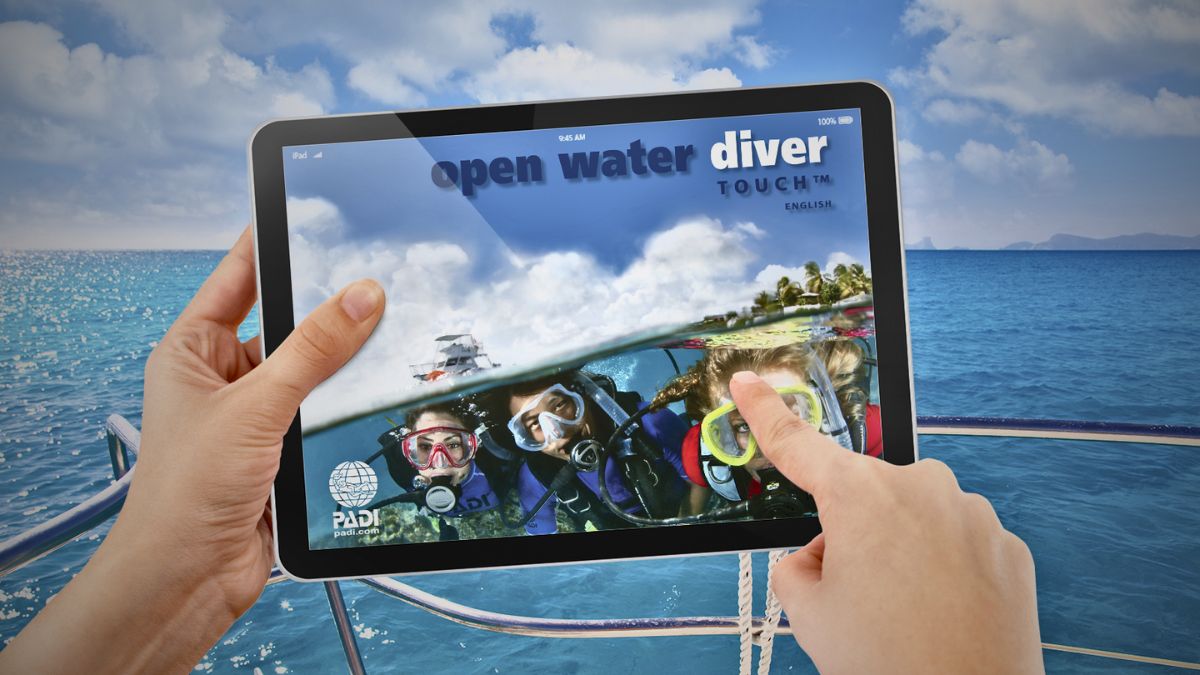 Student studying PADI eLearning scuba diving course on laptop at home showing online diving theory education and digital certification training interface