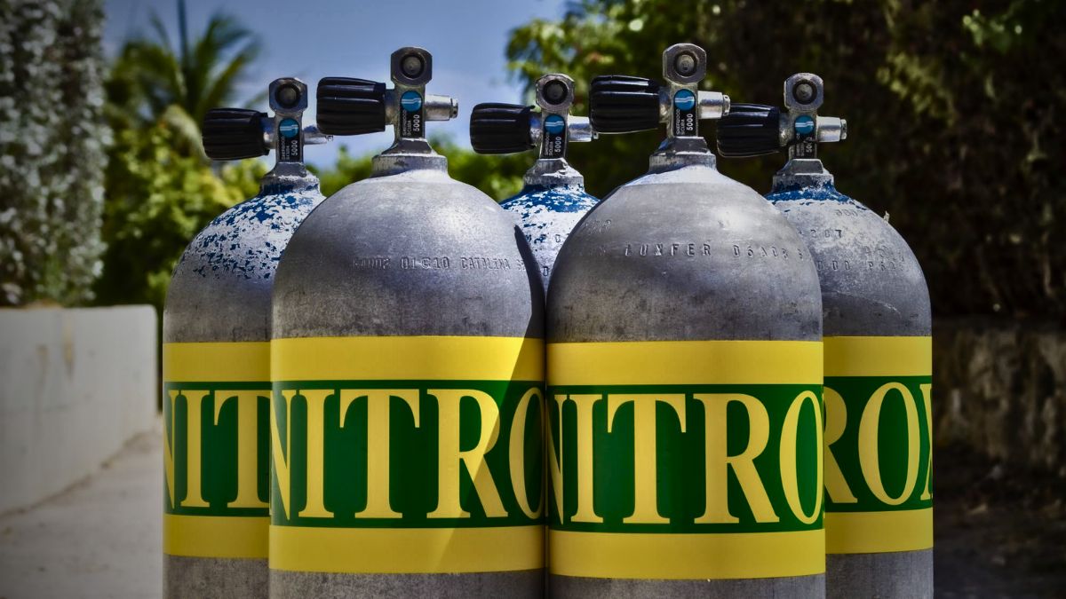 Scuba tank with yellow-green nitrox bands and clear "NITROX 32" sticker label standing on dive boat deck in Costa Rica showing enriched air diving equipment