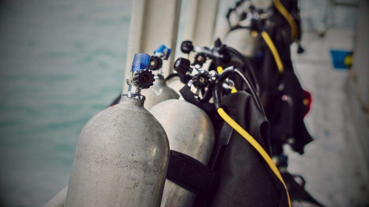 Close-up of scuba diving tank cylinder showing valve assembly markings and technical specifications in Costa Rica dive shop demonstrating tank structure and properties