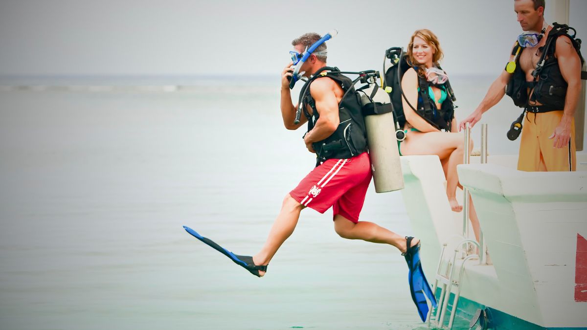 Scuba diver performing giant stride entry jumping from dive boat into Costa Rica ocean demonstrating proper water entry technique with full equipment