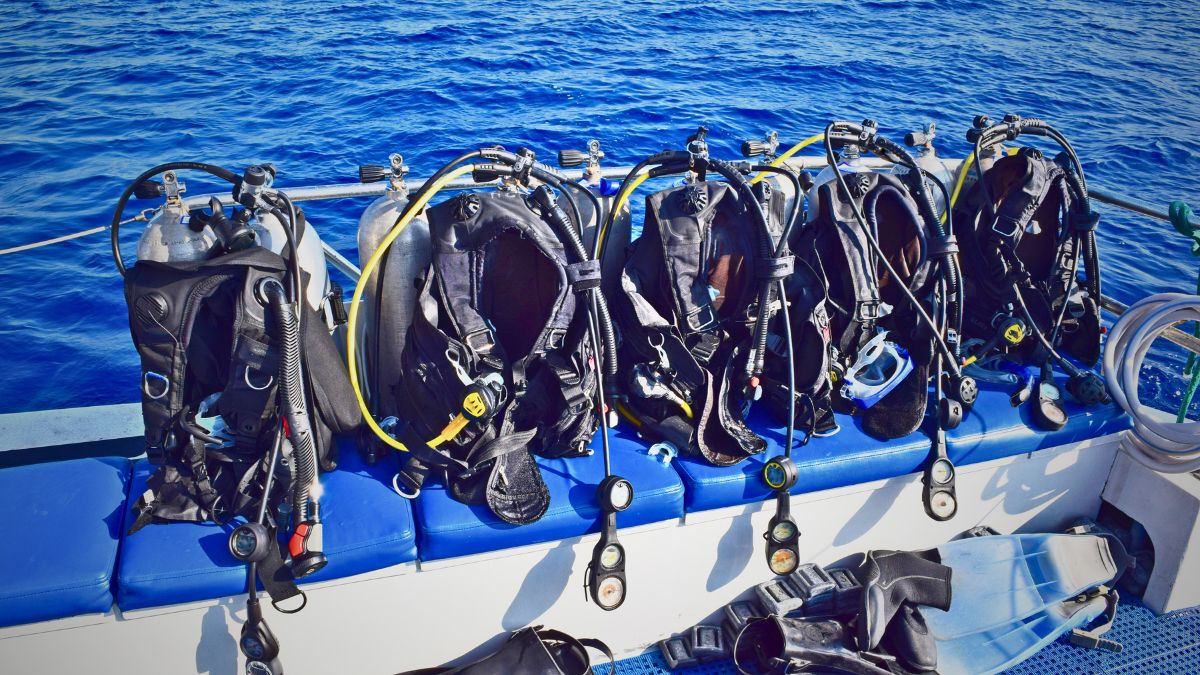 Customer comparing different BCD buoyancy compensator models in various styles and colors at Costa Rica dive shop showing equipment selection guide