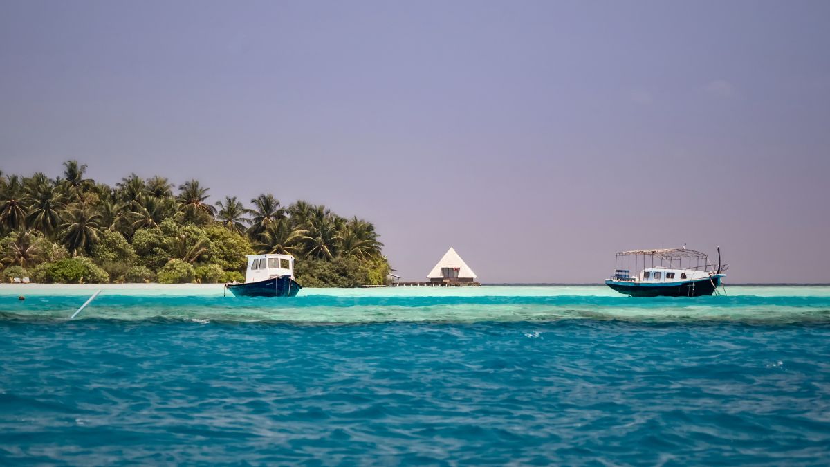 Is Scuba Diving in Maldives Worth It? Diver's Complete Guide » Costa Rica Divers Two small boats anchored on clear turquoise water in the Maldives, with gentle ripples visible on the lagoon surface