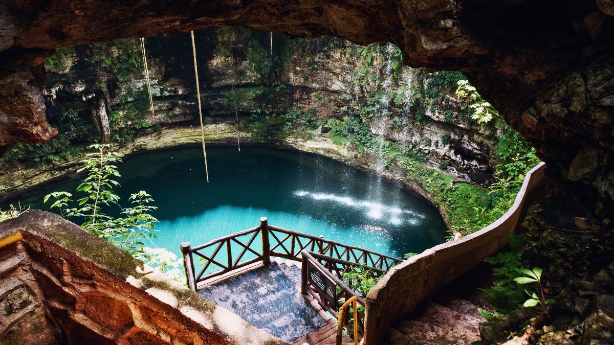 Scuba diver exploring spectacular underwater cenote cave with dramatic light beams and crystal clear water in Yucatan Mexico limestone formations