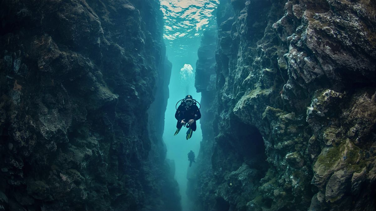Scuba diver in drysuit swimming through crystal clear Silfra fissure between tectonic plates with incredible visibility in Thingvellir National Park Iceland