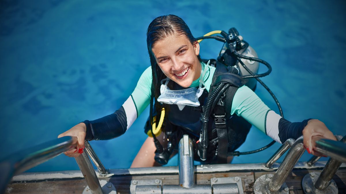 Two scuba divers performing buddy check and inspecting equipment on dive boat in Costa Rica showing proper pre-dive preparation and safety procedures