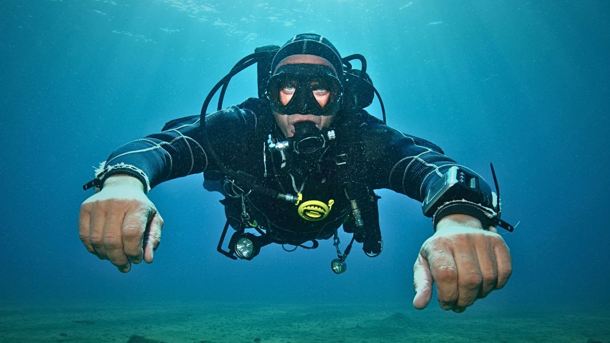 Scuba diver checking air pressure gauge and dive computer underwater monitoring air consumption for SAC rate calculation in Costa Rica