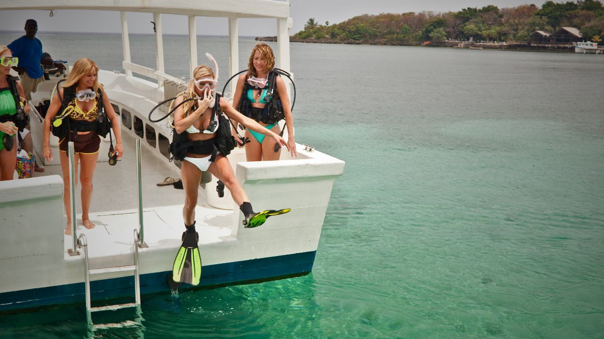 Excited female scuba divers on boat preparing for thrilling dive adventure with diving gear ready